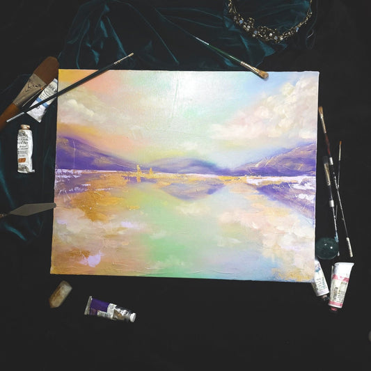 Painting of a landscape with colorful brushstrokes, surrounded by art supplies on a dark surface.
