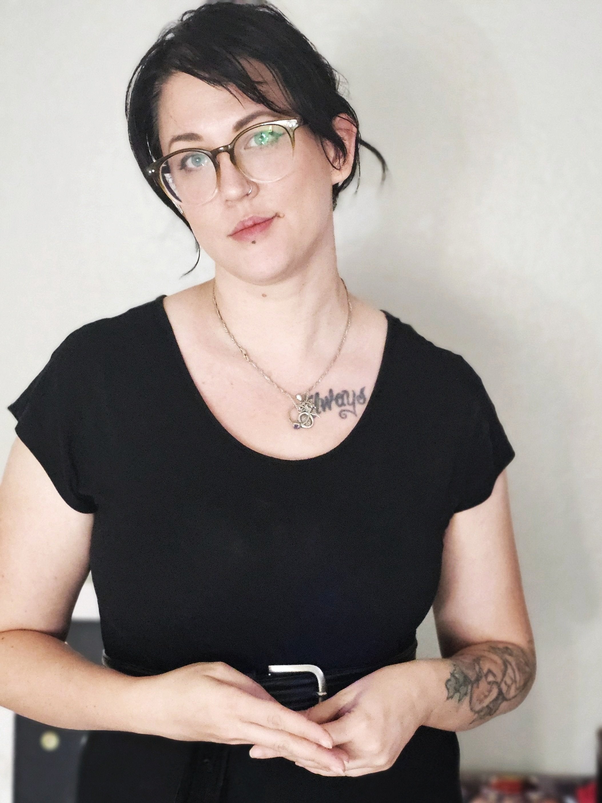 woman dressed in black with glasses and her hair in an updo looking forward. With a partial welcoming smile.